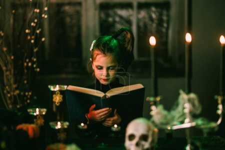 Foto de Retrato de una linda niña de Halloween con un enorme libro viejo. - Imagen libre de derechos