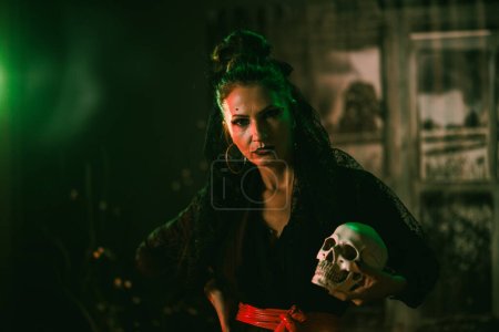 Photo for An attractive mature woman holding skull at Halloween party. Looking at camera. - Royalty Free Image