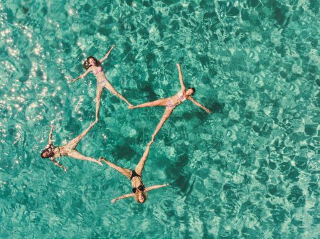 Téléchargez les photos : Photo aérienne d'une quatre belles amies se relaxant tout en flottant dans une eau tropicale turquoise. - en image libre de droit