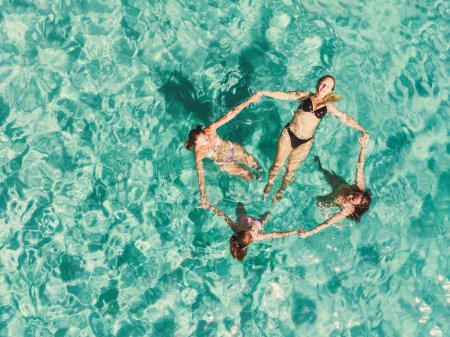 Foto de Foto aérea de cuatro hermosas amigas divirtiéndose en el mar despejado. - Imagen libre de derechos