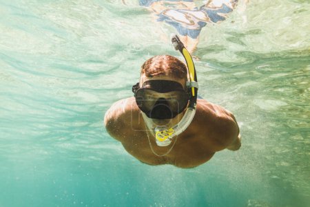 Foto de Hombre guapo divirtiéndose en las vacaciones de verano y explorando el fondo del mar durante el buceo en el mar. - Imagen libre de derechos