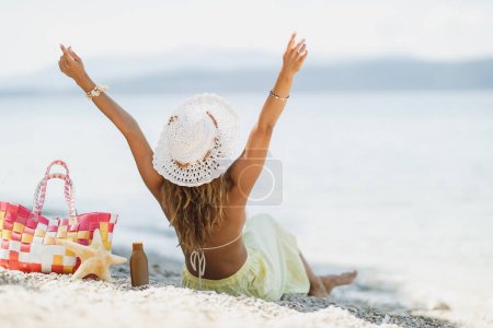 Foto de Vista trasera de una atractiva mujer en bikini, con sombrero de verano, se divierte mientras disfruta de unas vacaciones de verano en la playa. - Imagen libre de derechos