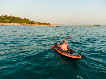 Téléchargez les photos : Tourné d'un homme méconnaissable qui pagaie en kayak dans une eau turquoise de la mer Ionienne pendant les vacances d'été. - en image libre de droit