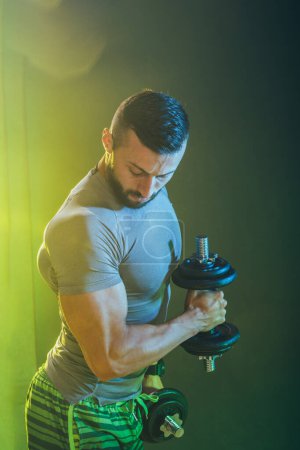 Photo for Shot of a muscular bodybuilder doing hard training with dumbbells. He is pumping up his triceps muscle with heavy weight. - Royalty Free Image