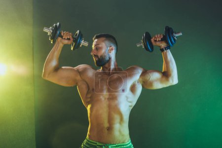 Foto de Foto de un musculoso culturista haciendo un duro entrenamiento con pesas. Él está bombeando su músculo de los hombros con peso pesado. - Imagen libre de derechos