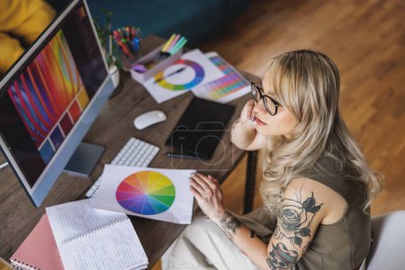Téléchargez les photos : Jeune femme créative regardant réfléchi tout en travaillant sur l'ordinateur dans son studio à la maison. - en image libre de droit