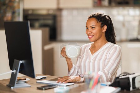 Téléchargez les photos : Femme d'affaires africaine profiter d'une tasse de café tout en travaillant à la maison. - en image libre de droit