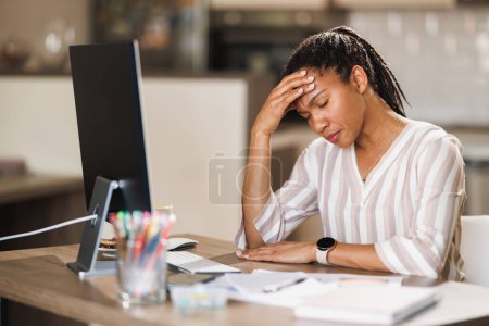 Téléchargez les photos : Femme d'affaires africaine regardant stressé tout en travaillant sur l'ordinateur de son bureau à domicile. - en image libre de droit