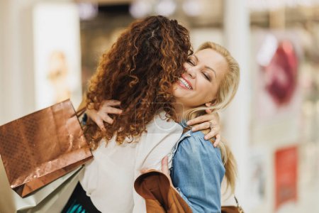 Téléchargez les photos : Coupé plan de deux gai petite amie coller ensemble lors d'une séance de shopping dans le centre commercial de la ville. - en image libre de droit