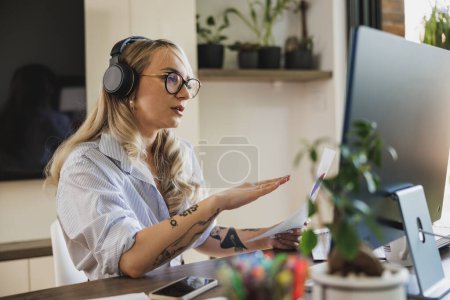 Téléchargez les photos : Jeune femme créative ayant réunion en ligne tout en travaillant à partir de son bureau à domicile. - en image libre de droit