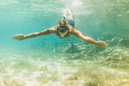 Téléchargez les photos : Beau homme s'amuser pendant les vacances d'été et explorer le fond marin pendant la plongée sous-marine en mer. - en image libre de droit