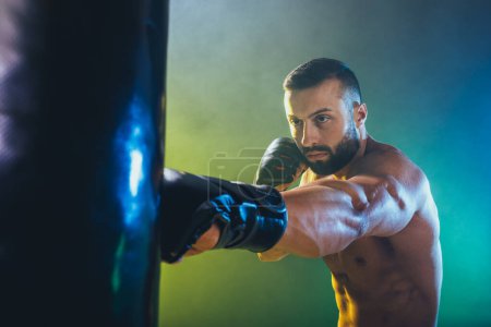 Photo for Shot of a muscular young male boxer working out on a punching bag. - Royalty Free Image