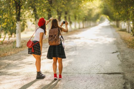 Foto de Vista trasera de un joven feliz dos mujeres están haciendo fotos durante caminar por la avenida. - Imagen libre de derechos