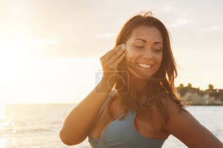 Photo for Portrait of a beautiful woman is relaxing on the beach in a sunny day. She is posing with smile on her face. - Royalty Free Image