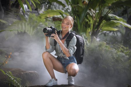 Téléchargez les photos : Portrait de belle jeune femme prend des photos dans la jungle - en image libre de droit