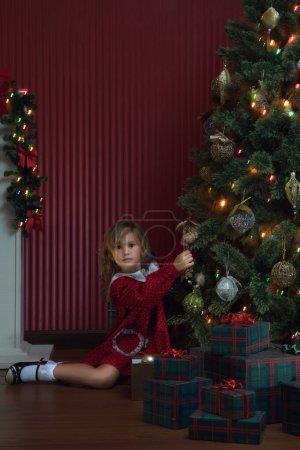 Téléchargez les photos : Portrait de petite fille est en attente pour Père Noël venir dans l'environnement domestique - en image libre de droit