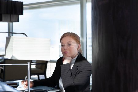 Téléchargez les photos : Portrait de jeune femme en costume noir dans un environnement de bureau - en image libre de droit
