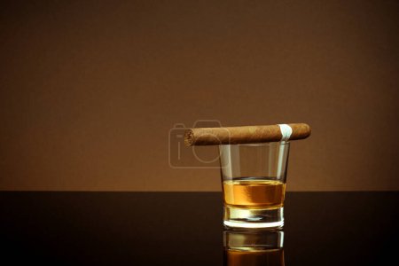 Téléchargez les photos : Vue fermée du verre de whisky avec cigare sur le dessus sur le dos blanc - en image libre de droit