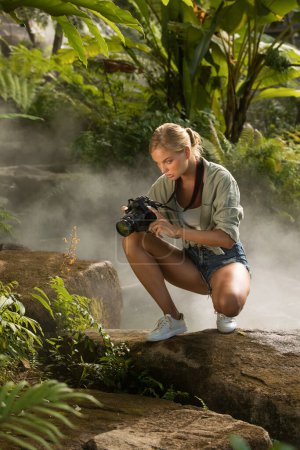Téléchargez les photos : Portrait de belle jeune femme prend des photos dans la jungle - en image libre de droit