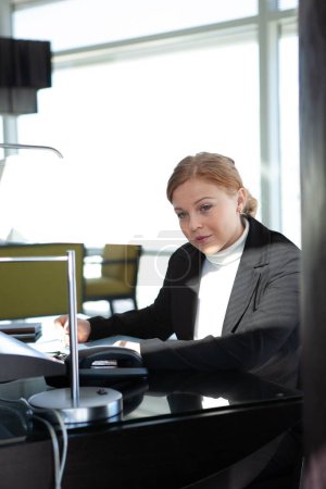 Téléchargez les photos : Portrait de jeune femme en costume noir dans un environnement de bureau - en image libre de droit