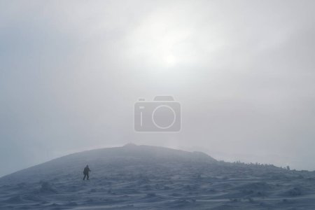 Téléchargez les photos : Homme marche avec un sac à dos dans la neige lors d'une randonnée en montagne par temps froid d'hiver - en image libre de droit