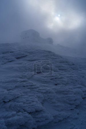 Photo for Severe winter weather with frost and snow in the mountains. Old observatory in the clouds on top of a mountain, Carpathians, Ukraine - Royalty Free Image