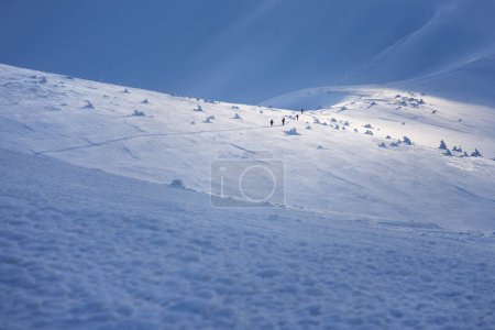 Téléchargez les photos : Un groupe de touristes lors d'une randonnée hivernale en montagne avec des sacs à dos à travers un champ enneigé - en image libre de droit
