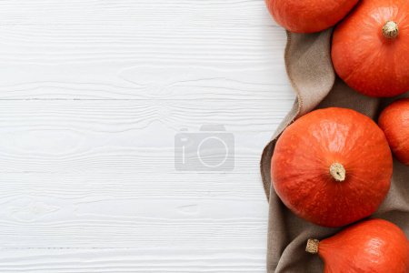 Téléchargez les photos : Récolte de courge Kuri rouge sur un fond en bois blanc avec espace de copie - en image libre de droit