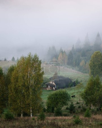 Téléchargez les photos : Paysage avec vue sur une maison abandonnée dans un village de montagne avec brouillard matinal - en image libre de droit