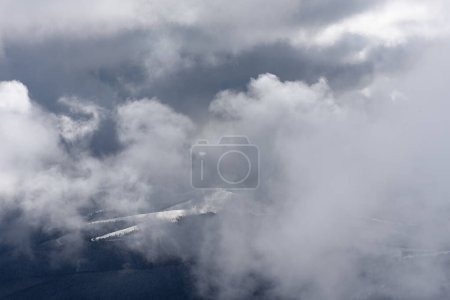 Téléchargez les photos : Paysage hivernal avec nuages suspendus bas dans les montagnes et la vallée enveloppé dans brume - en image libre de droit