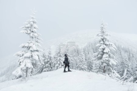 Téléchargez les photos : Homme avec caméra en randonnée hivernale dans les montagnes enneigées - en image libre de droit