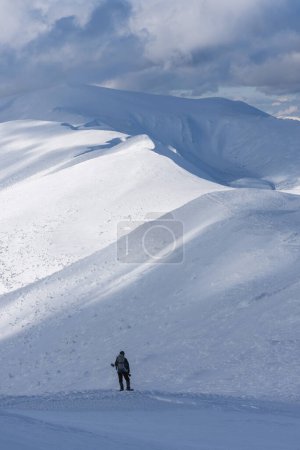 Photo for Backpacker with Snowshoes in Snow-Covered Peaks - Royalty Free Image