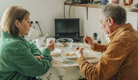 Téléchargez les photos : Elderly couple sitting at a table and having lunch - en image libre de droit