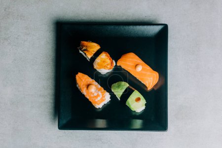 Foto de Sushi tradicional con salmón, anguila y atún en plato negro - Imagen libre de derechos