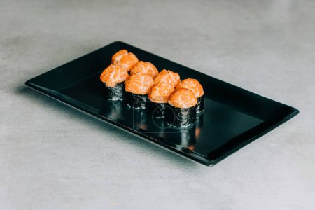 Téléchargez les photos : Rouleaux de sushi avec saumon et caviar sur plaque noire sur fond gris - en image libre de droit