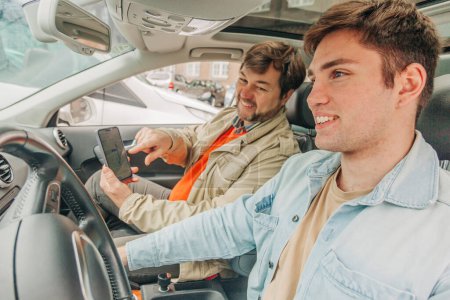 Téléchargez les photos : Père et fils ont une discussion à l'intérieur de la voiture sur la navigation dans le smartphone - en image libre de droit