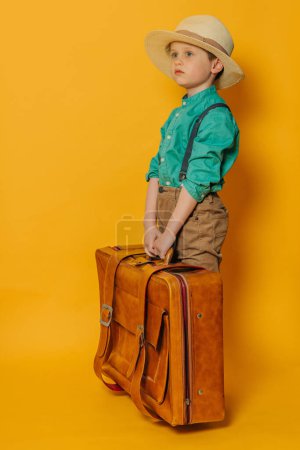 Foto de Niño en sombrero, tirantes y camisa verde con bolsa sobre fondo amarillo - Imagen libre de derechos