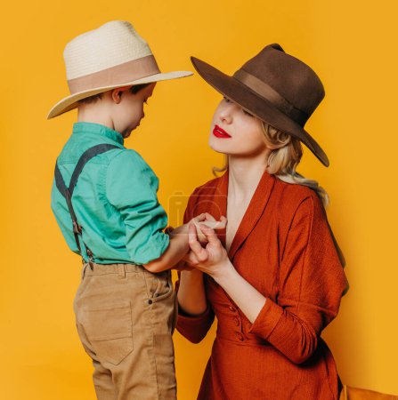 Téléchargez les photos : Mère et fils élégants en vêtements vintage sur fond jaune - en image libre de droit