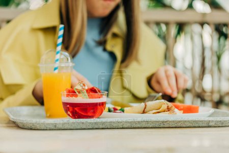 Foto de Chica comiendo panqueques y jalea en la mesa en el café - Imagen libre de derechos