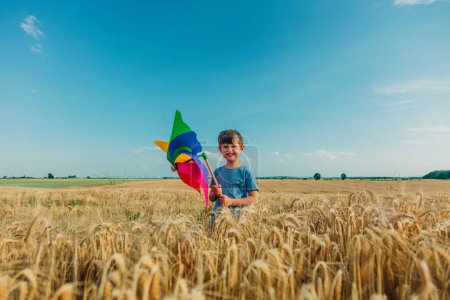 Foto de Niño en camisa azul con volante en campo de trigo amarillo en verano - Imagen libre de derechos