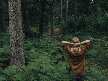 Foto de Mujer se encuentra entre helechos y pinos en el bosque - Imagen libre de derechos