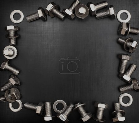 Photo for Frame of bolts and shims on a black scratched metal surface - Royalty Free Image