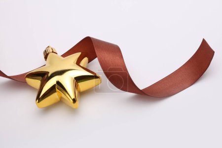Photo for Close-up Christmas gold glitter star with brown ribbon on beige copy space background. - Royalty Free Image