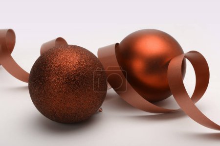 Photo for Close-up red brown glitter texture nacre and glow Merry Christmas ball, ribbon on beige background. - Royalty Free Image