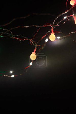 Téléchargez les photos : Doux foyer flou lampe de Noël guirlande lumières sur fond abstrait mur sombre. - en image libre de droit