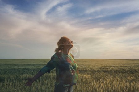 Téléchargez les photos : Femme heureuse lever la main sur le champ de blé et ciel paysage doux. Léger ton pastel délicat. Nature fond horizontal avec espace de copie. - en image libre de droit