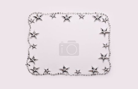 Photo for Silver star garland frame on light beige empty copy space background. - Royalty Free Image