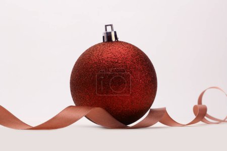 Foto de Close-up rojo marrón brillo textura nácar y brillo Feliz bola de Navidad, cinta sobre fondo beige. - Imagen libre de derechos