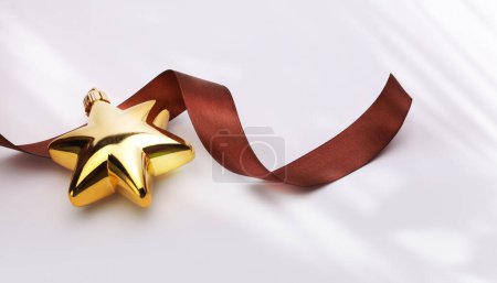 Foto de Close-up estrella de brillo de oro de Navidad con cinta marrón en el espacio de copia beige fondo horizontal. - Imagen libre de derechos