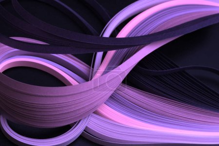 Foto de Color de neón violeta tira de papel ondulado. Textura abstracta fondo negro. - Imagen libre de derechos